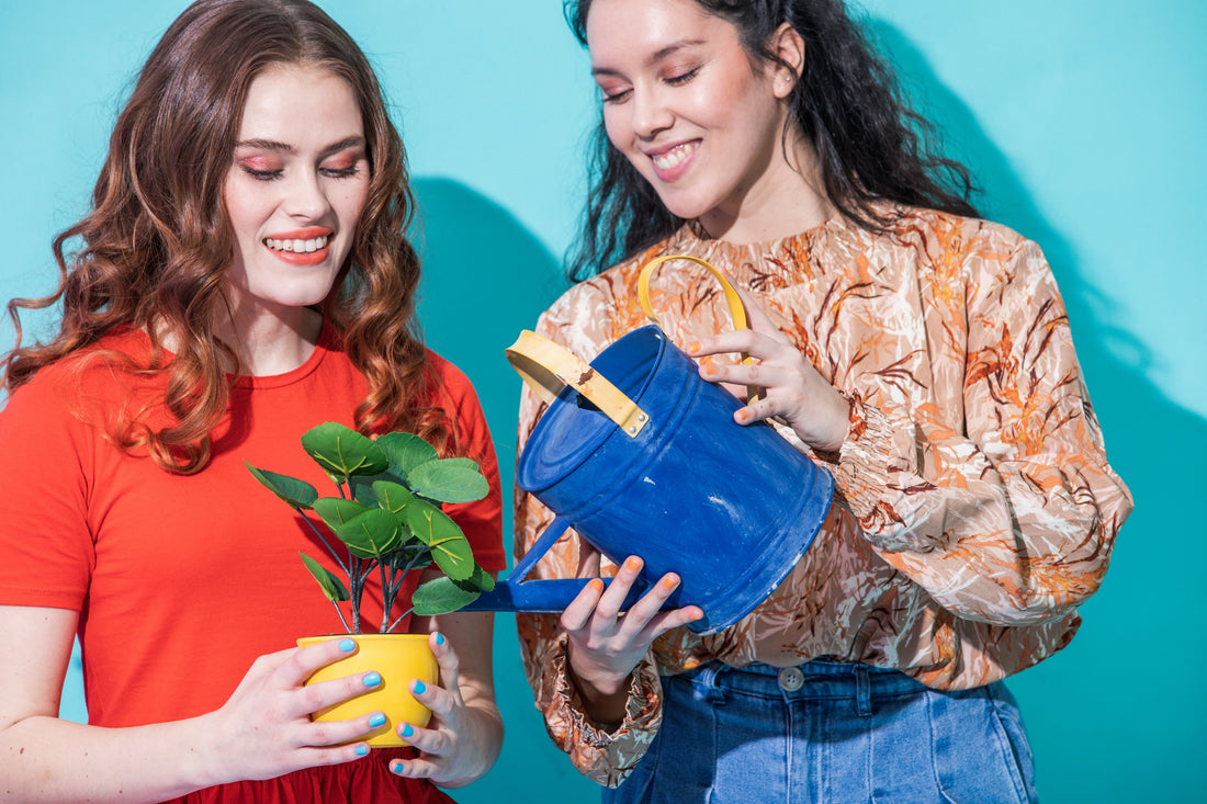 two women watering a plant 